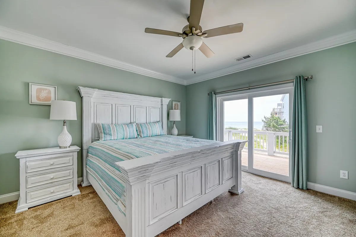 A tranquil bedroom with a welcoming bed, a nightstand, and sliding glass doors that open to a balcony or deck. The set-up allows for morning sunlight and a seamless transition from private comfort to outdoor enjoyment.