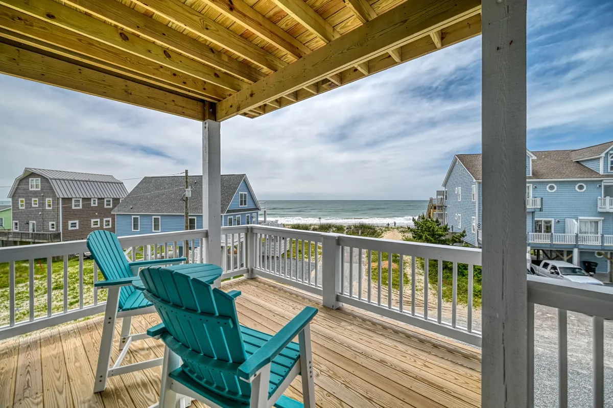 A tranquil private porch with blue chairs set on a wooden deck, overlooking sweeping ocean views. The inviting setup is perfect for quiet mornings or sunset relaxation, extending the bedroom sanctuary outdoors.