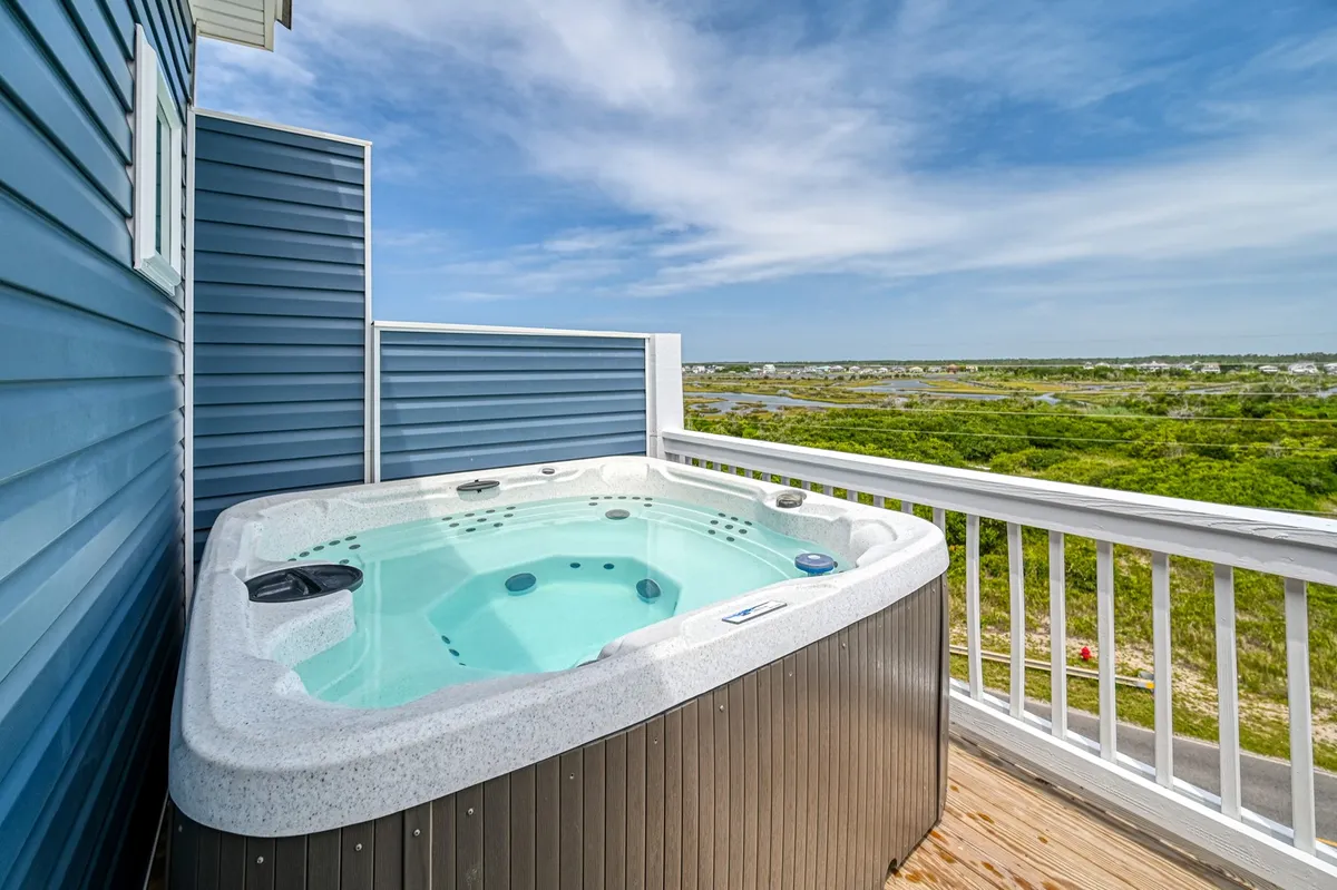 A tranquil sound side deck with a bubbling hot tub, wooden decking, and expansive views of the surrounding landscape. The space is perfect for relaxing in the hot tub during sunset or enjoying morning coffee outdoors.